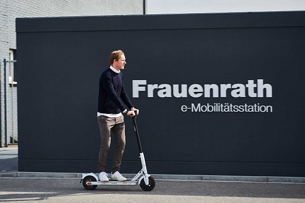 Person fährt auf E Scooter über das Firmengelände von Frauenrath